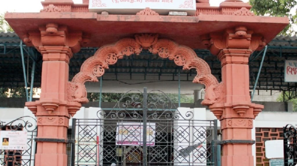 Jain temple entrance with red arched gateway and carvings in Ahmedabad, India.